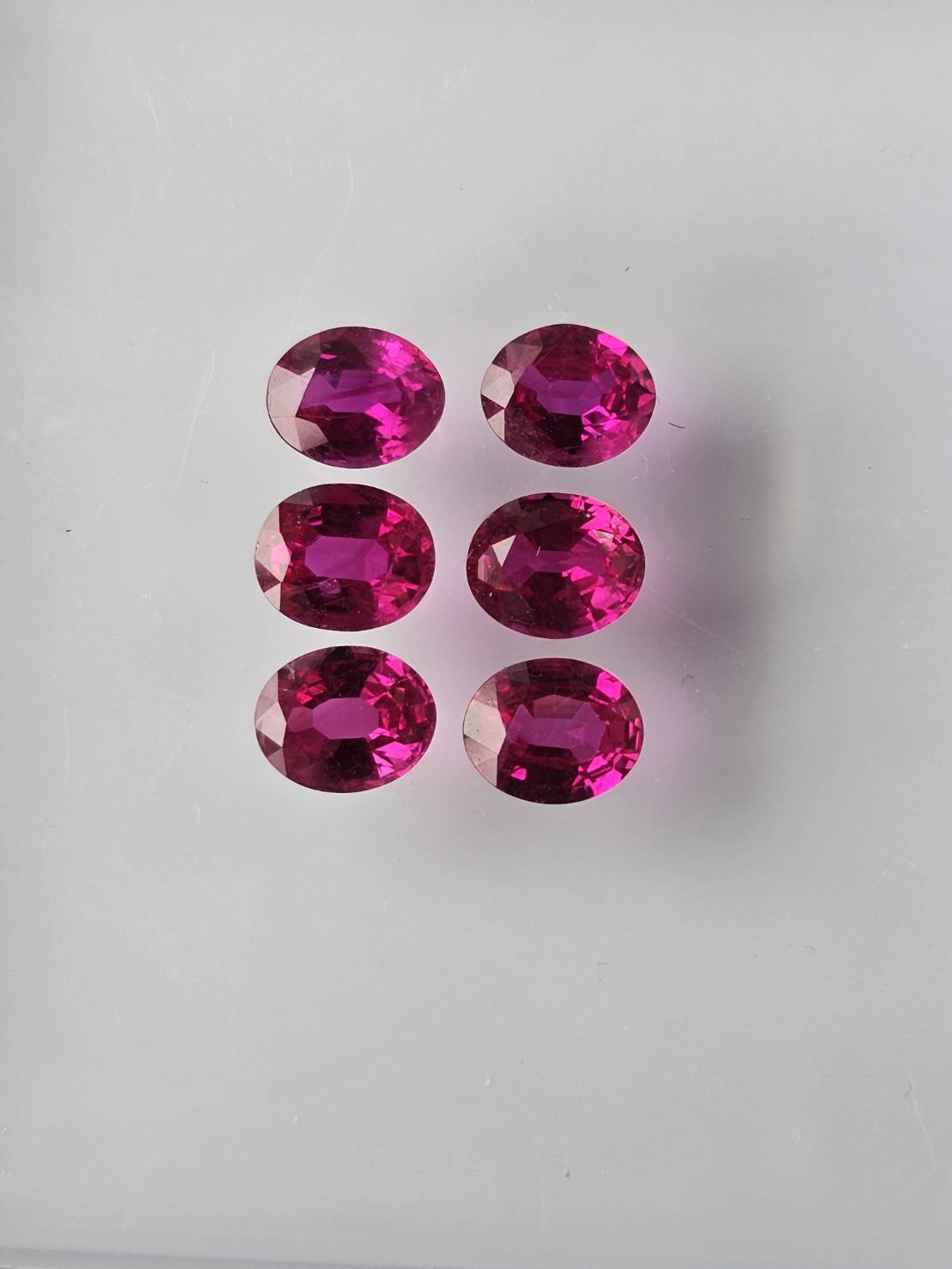 Six oval ruby stones photographed in a gem tray