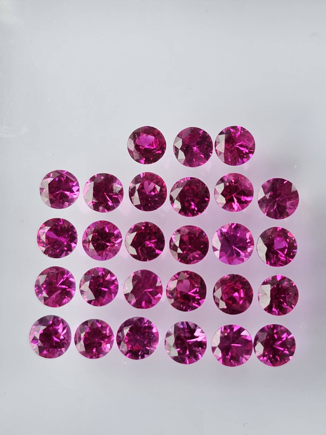 Parcel of small round ruby stones arranged in a gem tray